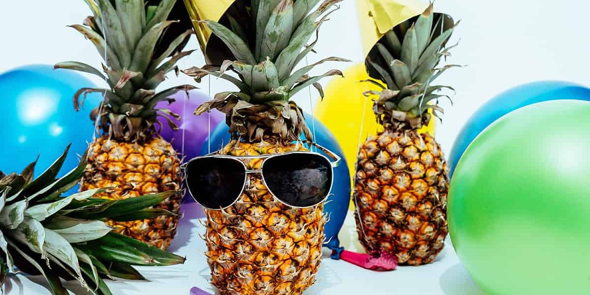 Eine dekorierte Annanas im Partylook zwischen Ballons