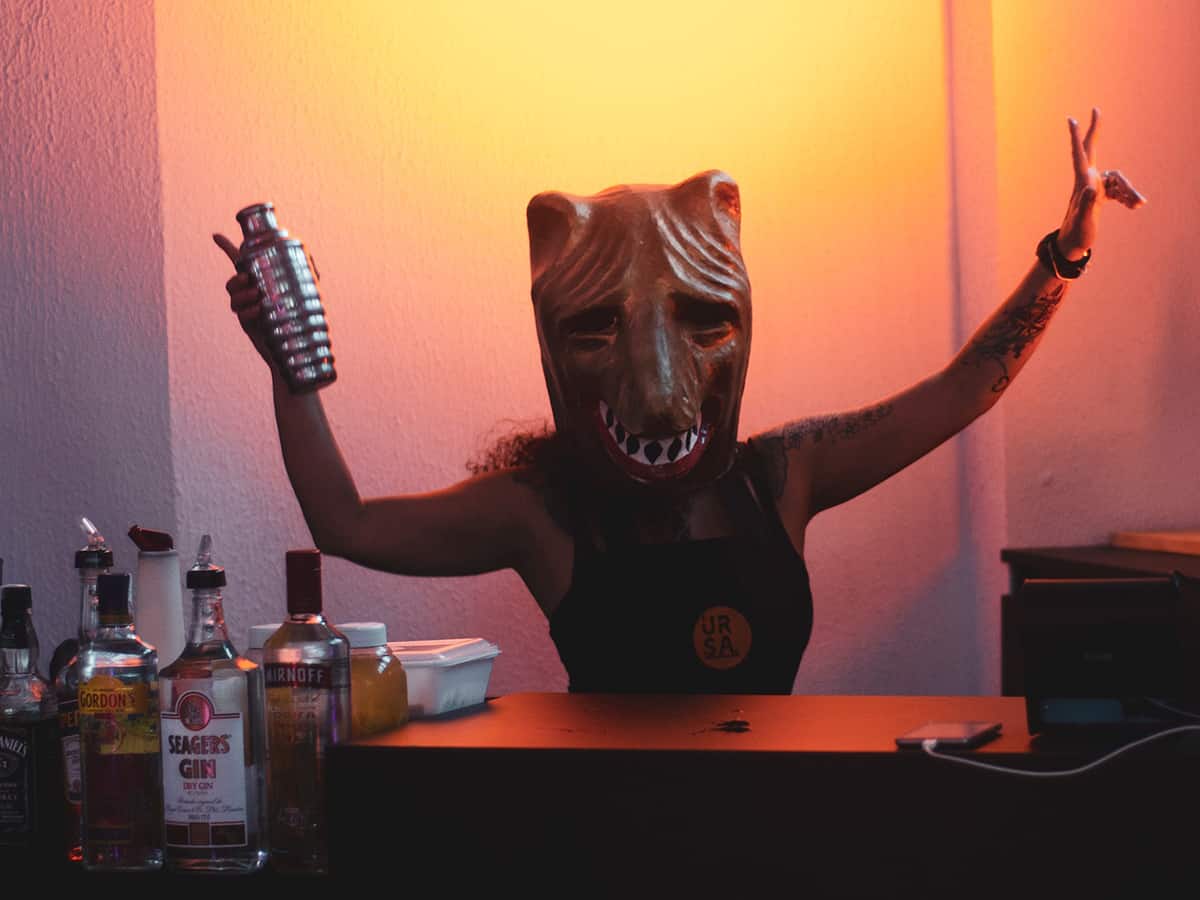 Es ist Zeit für Verkleidungen! Karnevalistin mit einer Wolfsmaske mixt einen Cocktail.