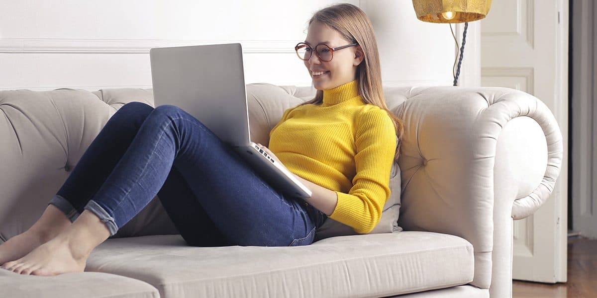 Mädchen sitzt mit Ihrem Notebook auf der Couch