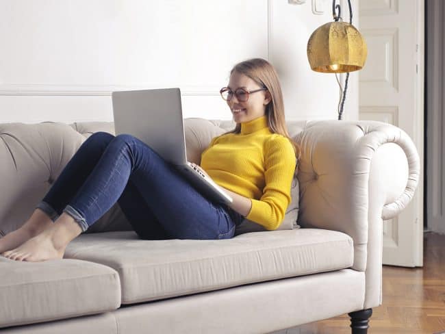 Mädchen sitzt mit Ihrem Notebook auf der Couch