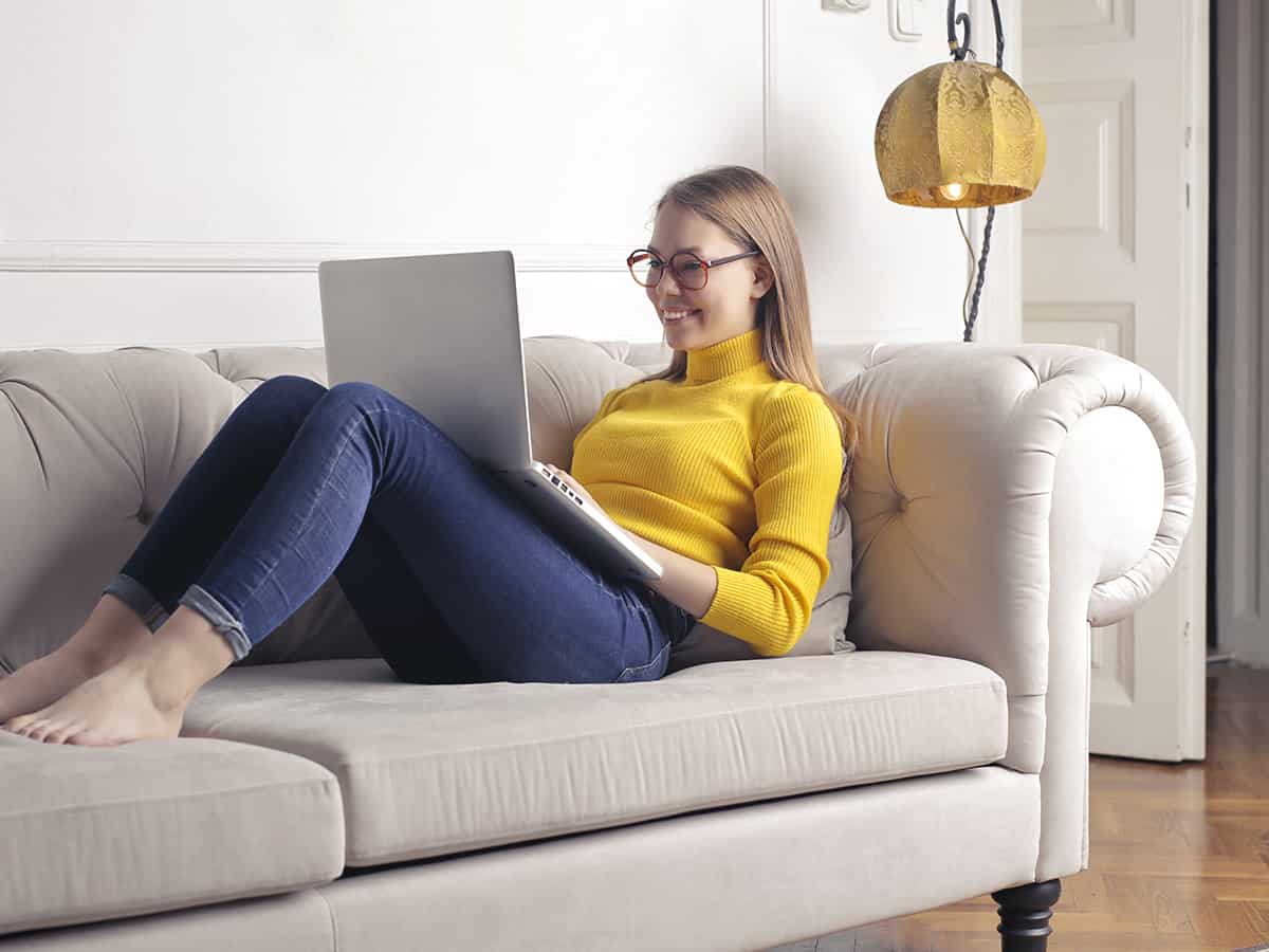 Mädchen sitzt mit Ihrem Notebook auf der Couch