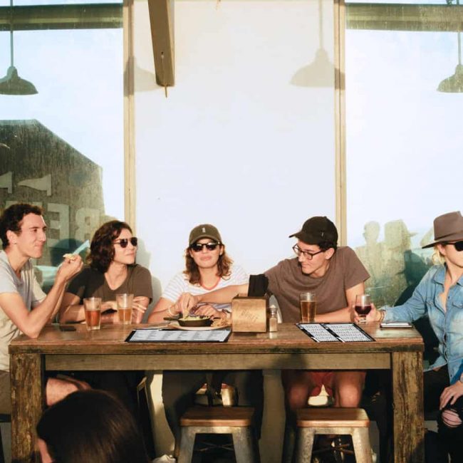 Stadt Land Fluss Partyspiel Freunde sitzen in der Abendsonne und spielen das Partyspiel Stadt Land Unseriös