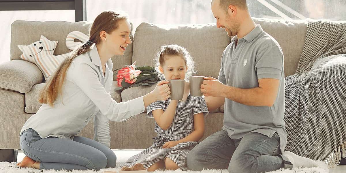 Familie sitzt auf dem Teppich im Wohnzimmer