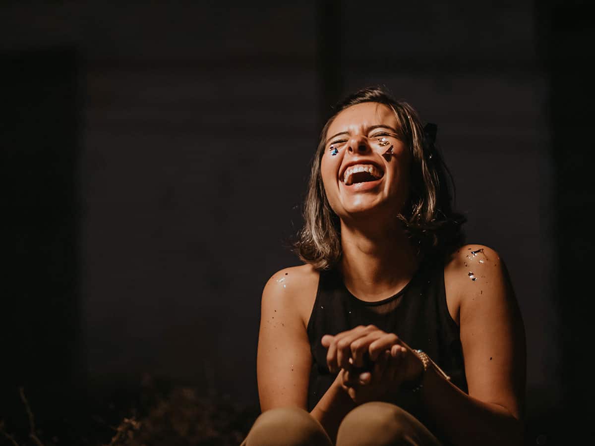 Flachwitze und Kalauer - eine Frau lacht auf einer Party über einen Witz
