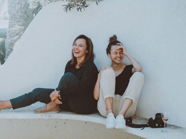 Lustig durch den Sommer. Mädchen lachen über einen Flachwitz bei einem Glas Wein.