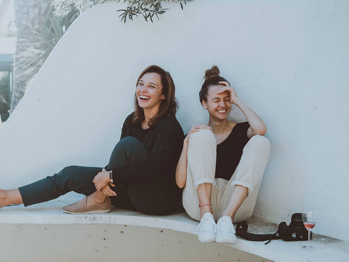 Lustig durch den Sommer. Mädchen lachen über einen Flachwitz bei einem Glas Wein.